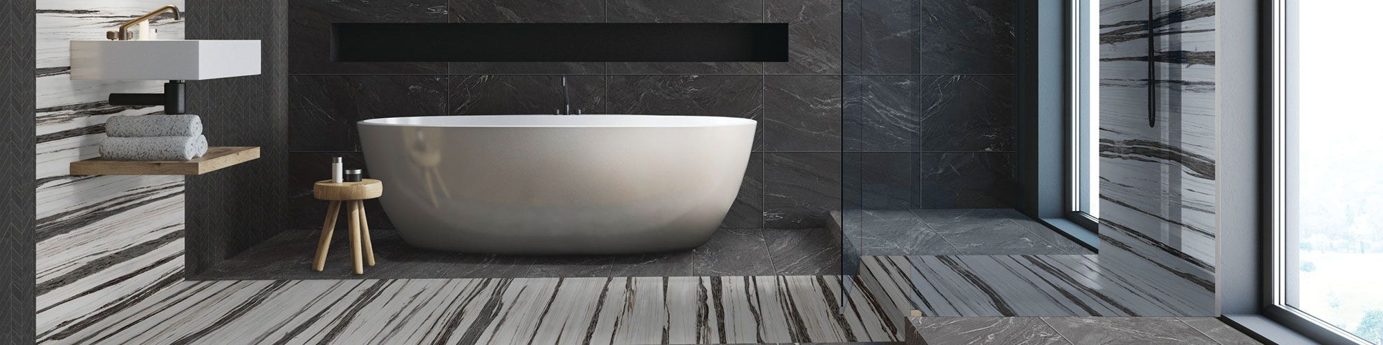 Modern décor wet room with white soaker tub, shower wall, floor, and niche of black marble look tile with white & black tile accents, floating vanity countertop & shelf.