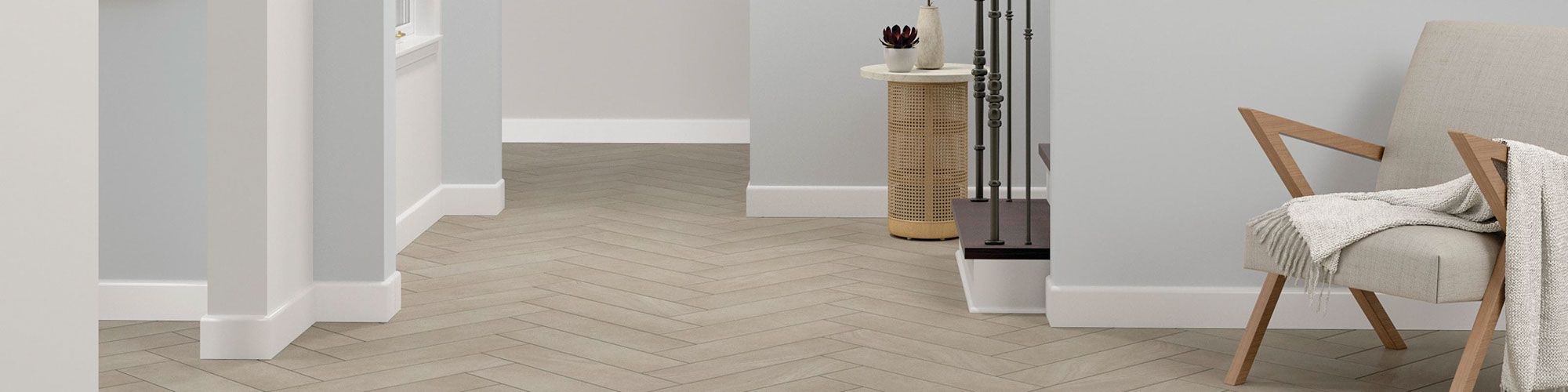 Foyer with gray floor tile that looks like stone set in a herringbone pattern, wood chair with off-white cushions.