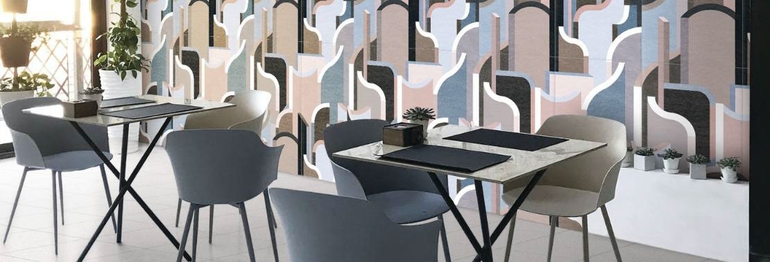 Restaurant with gray stone look floor tile, large-format ceramic wall tile with blue, pink, beige, black and white designs, dining tables with chairs.