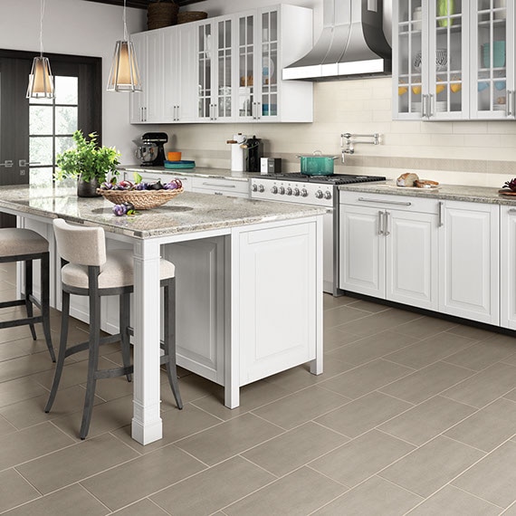 Kitchen with white cabinets and island. Lathe-turned corner post supporting island countertops. Concrete-look twelve by twenty-four inch porcelain tile floor in a light grey.