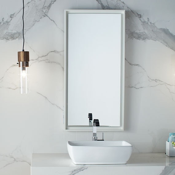 Bathroom vanity with white marble-look, porcelain slab backsplash and countertop, white vessel sink, framed mirror, and pendant lighting.