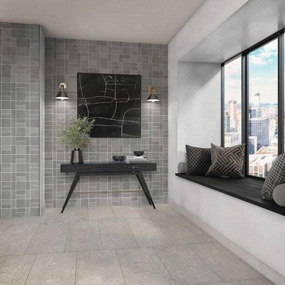 Highrise corridor with feature wall of intentionally imperfect gray wall tile in a basketweave horizontal pattern, gray stone look floor tile, and window seat.