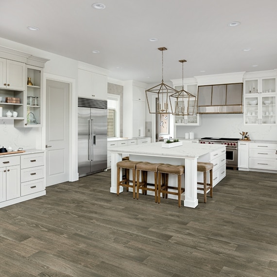 Transitional kitchen with floor tile that looks like wood, white cabinets, white quartz with gray veining countertops, island, and backsplash.