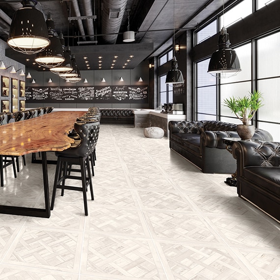 Industrial conference room with cassettone pattern floor tile that looks like white-washed wood, raw edge long table with leather chairs, and leather couches.