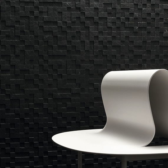 White abstract sculpture in front of black, 3D mosaic wall tile.
