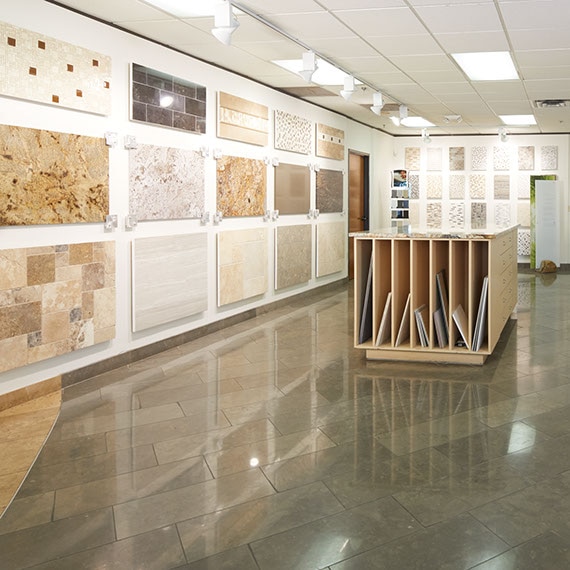 Daltile showroom with workstation and loose tile samples, walls covered by tiled panels of different tiles and patterns.