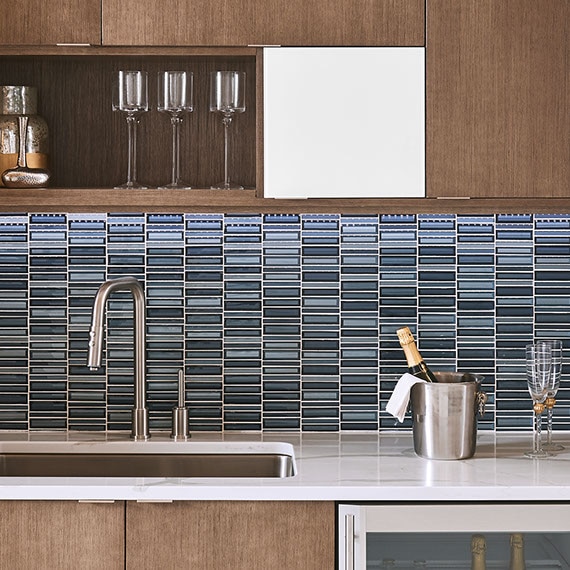 Kitchen with medium brown wood cabinets in a modern style with blue glass rectangular mosaic in a grid arrangement.