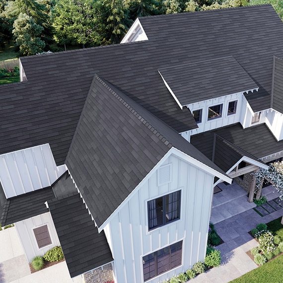 Bird's eye of modern farmhouse with black slate porcelain roof, white wood siding, concrete look porcelain paver front walkway & porch.