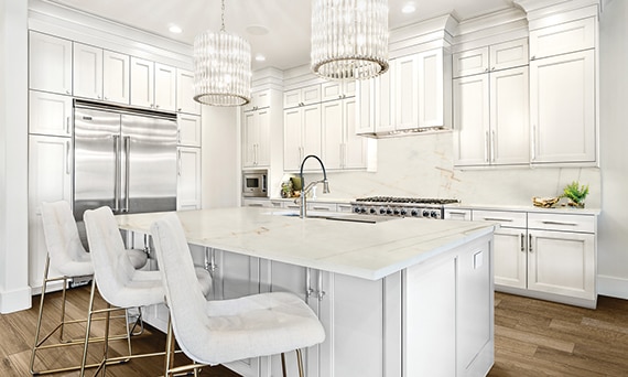 Eat-in kitchen with pendant lighting, white & tan quartzite counters, island with built in sink, white cabinets, stainless steel gas stove and refrigerator.