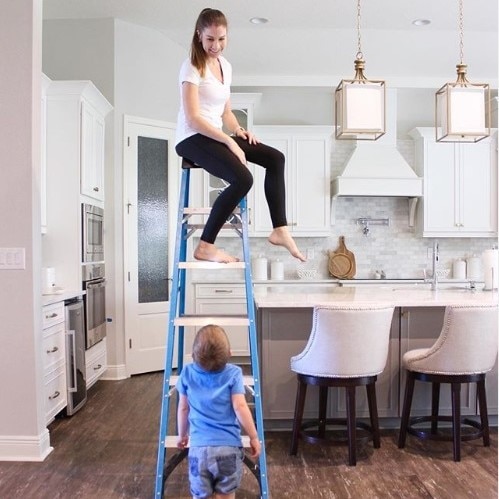 Lindsay Dean on a ladder with her son looking up at her.